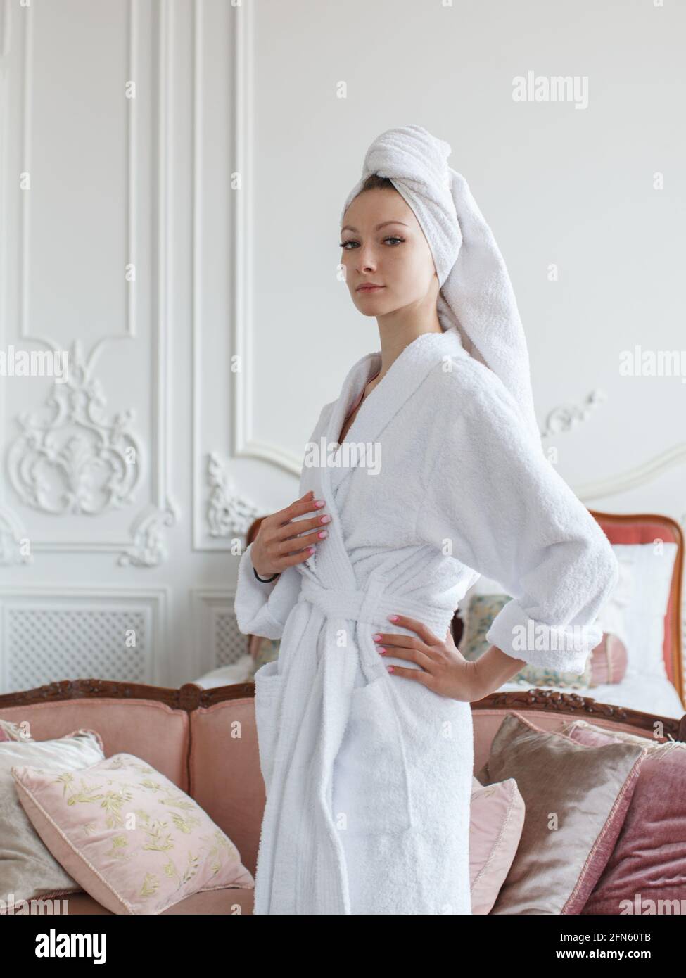 Attraktive Frau in weißem Bademantel im Schlafzimmer am Morgen Stockfoto