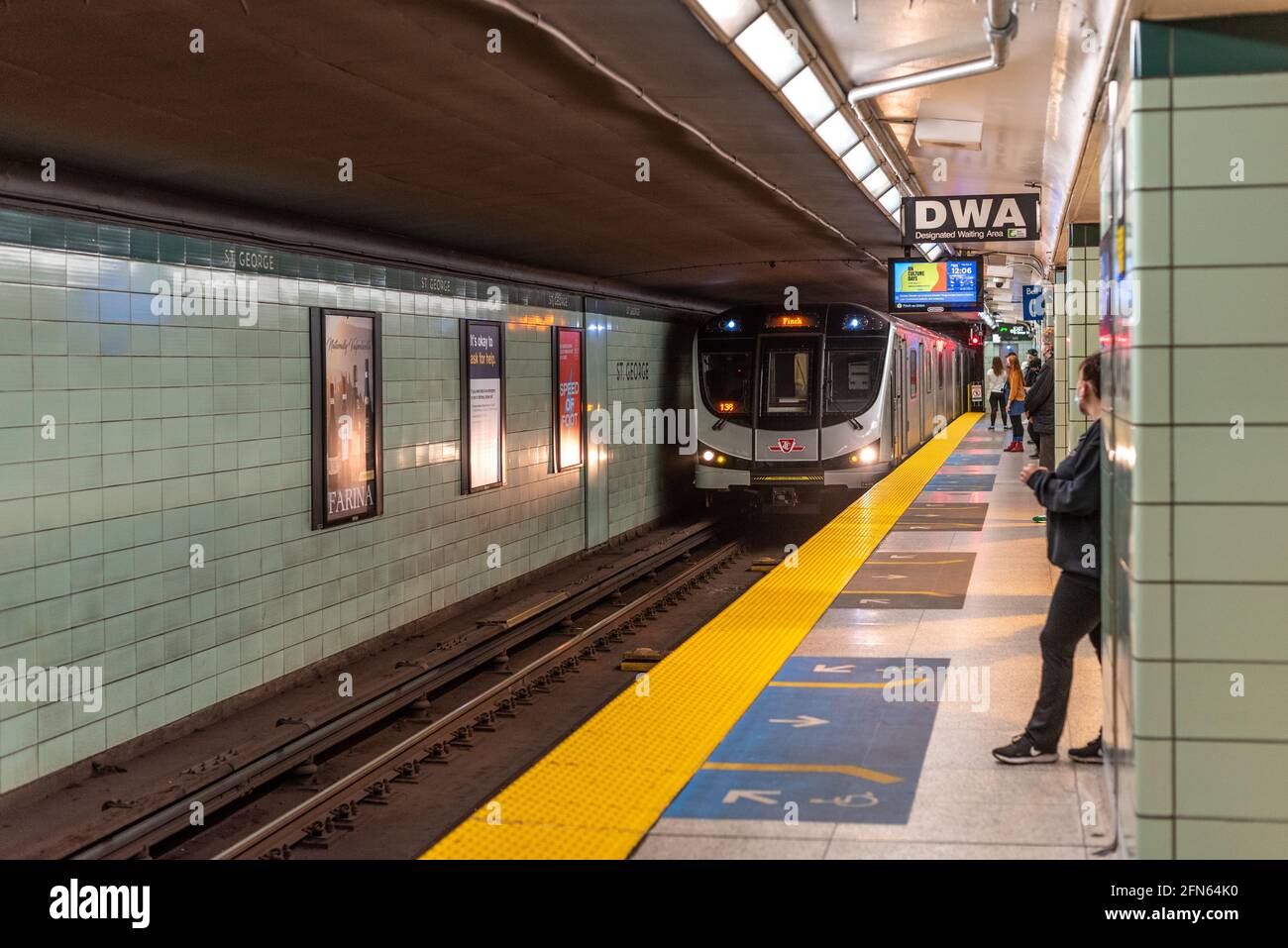 Echte Leute, die während der Coronavirus- oder Covid-19-Zeit auf einen TTC-U-Bahn-Zug in einem Bahnhof warten. TTC steht für Toronto Transit Commission in Kanada Stockfoto
