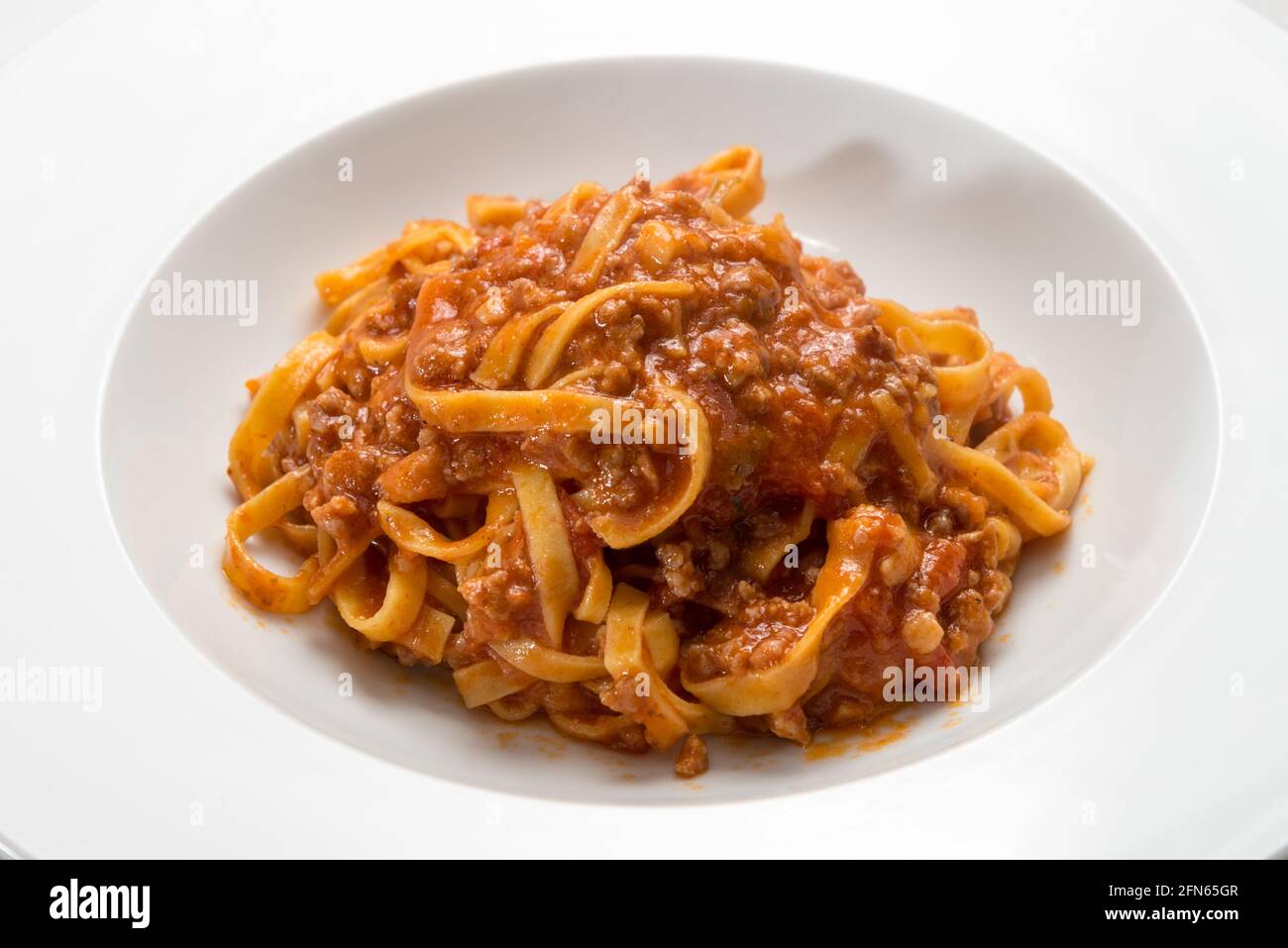 Italienische Tagliatelle mit Fleisch- und Tomatensauce, Nahaufnahme auf einem weißen Teller Stockfoto