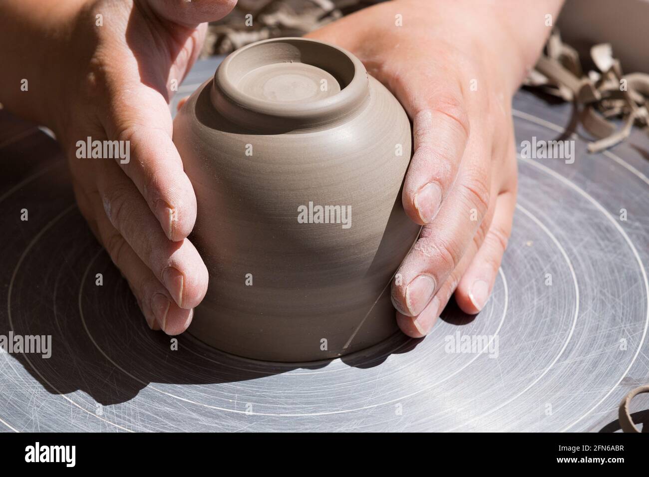 Töpfer Hände gekonnt fühlen die Basis nach dem Drehen und die Hand werfen eine Keramik geworfen Ton Vase Topf auf einem drehenden Rad. England. VEREINIGTES KÖNIGREICH (123) Stockfoto