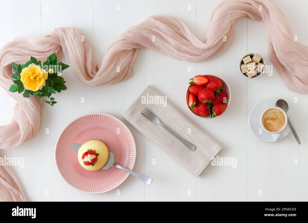 Hausgemachte Zitrone No-Bake Käsekuchen Kuppel mit frischen Erdbeeren. Weißer Holztisch mit gelben Rosées im Hintergrund. Stockfoto