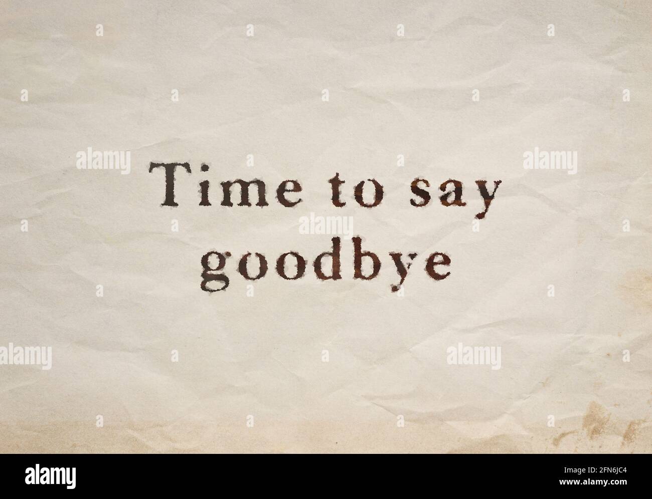 Nahaufnahme des Textes „Time to Say Auf Wiedersehen“ auf einem alten, befleckten und zerknittert beigefarbenen Papier. Stockfoto