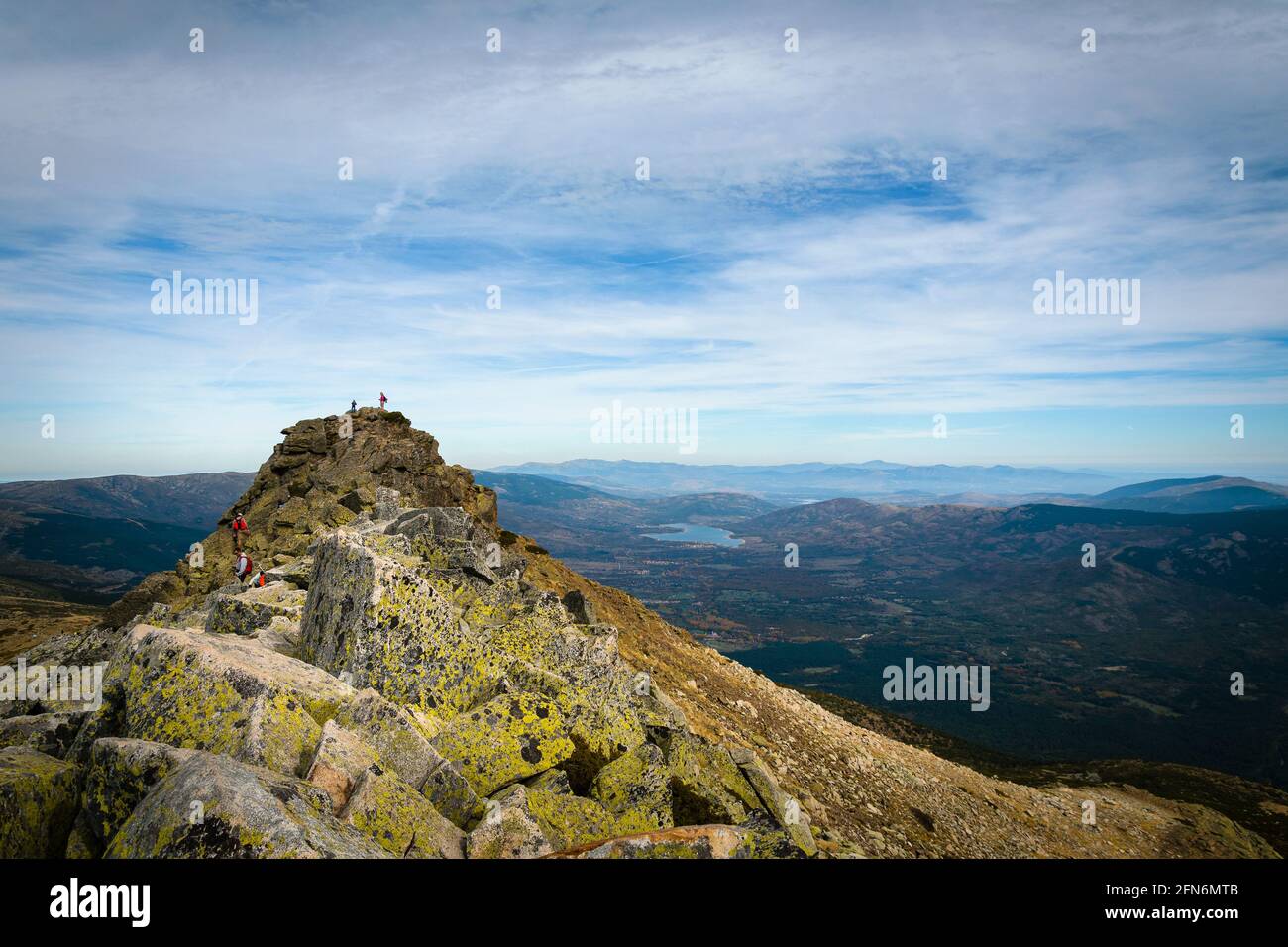 Menschen, die auf den Gipfel des Berges klettern, mit Blick auf das Lozoya-Tal im Hintergrund, Peñalara, Madrid, Spanien Stockfoto