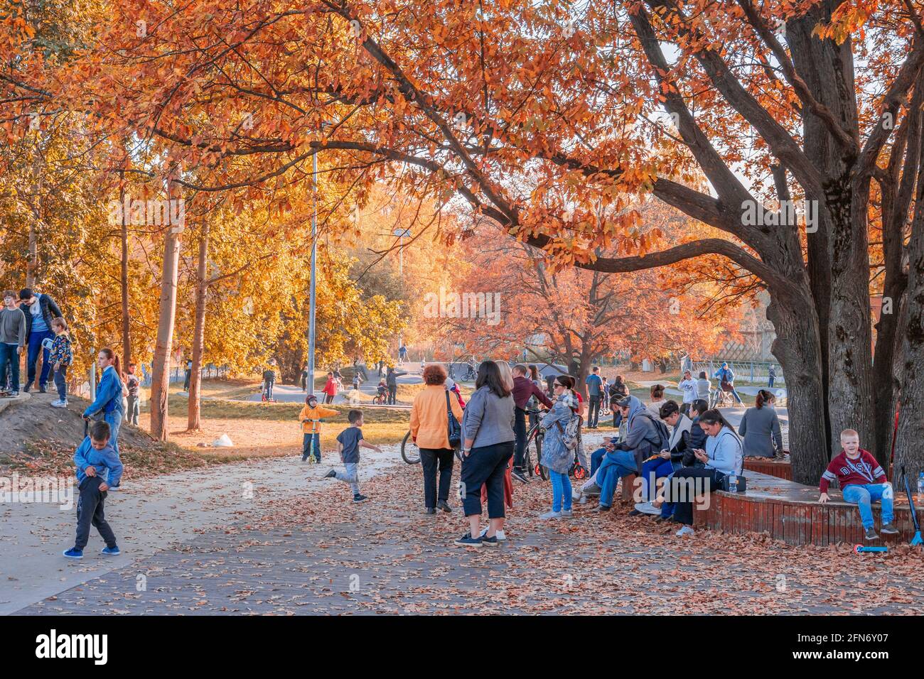 Kazan, Russland - 03. Oktober 2020: Kinder auf Fahrrädern und Motorroller und ihre Eltern im Skatepark im Stadtpark, sonniger Herbsttag. Stockfoto