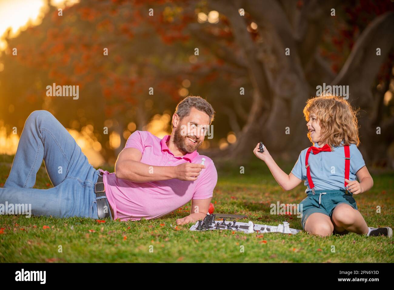 Vater spielt Schach mit Sohn. Familie draußen Spiel. Intelligentes Kind, intelligente Kinder. Stockfoto