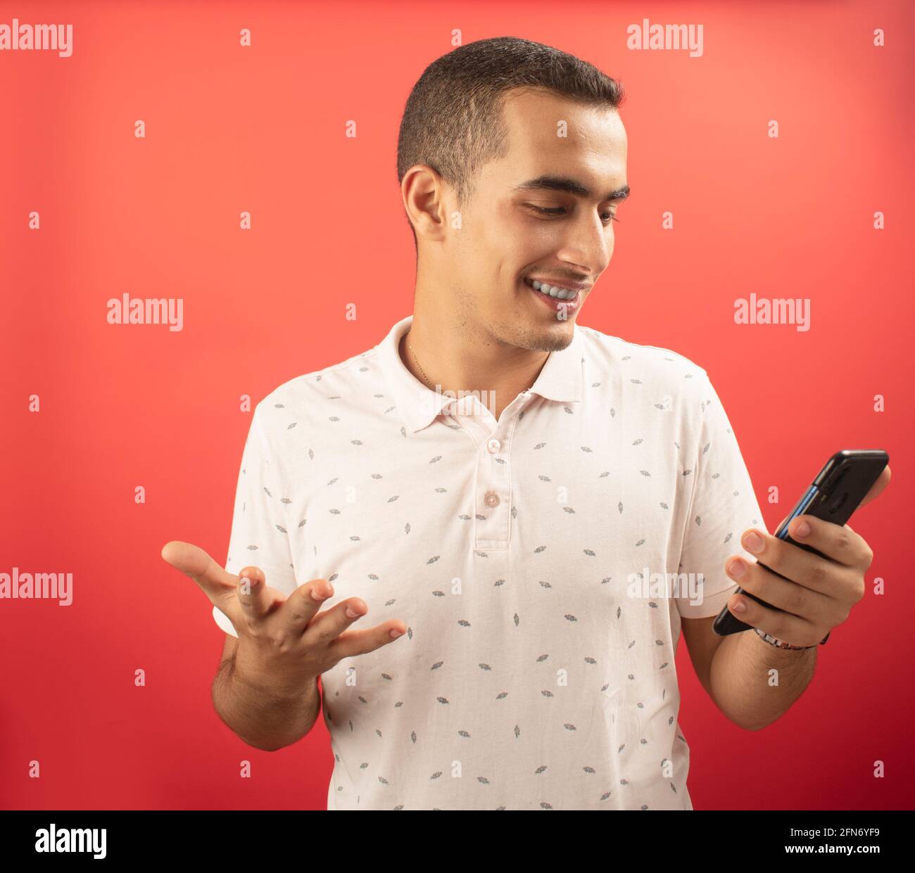 Ein junger Mann zeigt auf sein Telefon Stockfoto