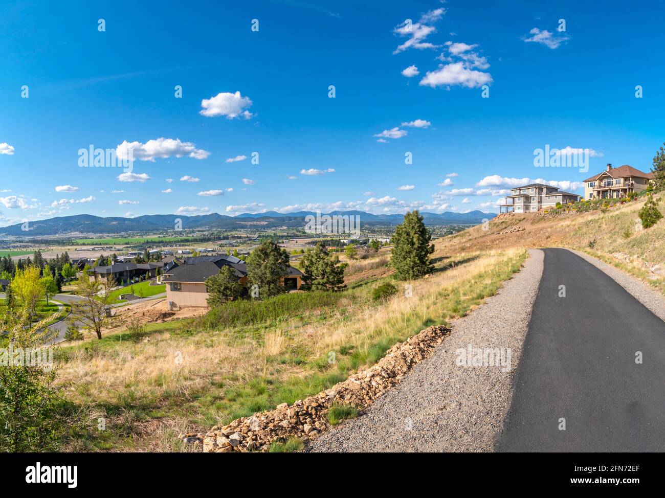 Blick von einem Betonwanderweg auf der Spitze eines Hügels in Liberty Lake, mit neuen Luxushäusern, die mit Blick auf das Spokane Valley, Newman Lake, Stockfoto