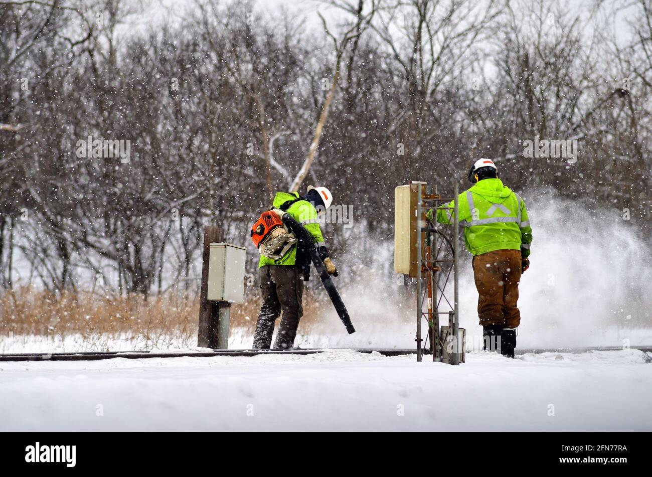 Elgin, Illinois, USA. Eisenbahnarbeiter arbeiten daran, Schnee von Schaltpunkten und Gleisen der Canadian National Railway zu entfernen. Stockfoto