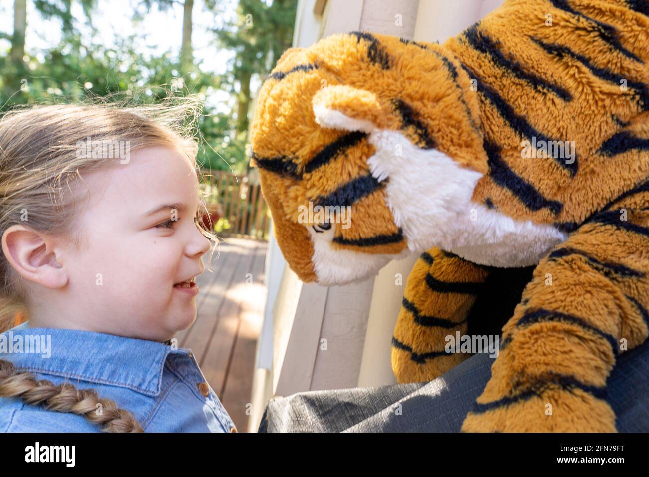 Lynwood, Washington, USA. Vier Jahre altes Mädchen, das draußen mit ihrem ausgestopften Tiger einen Stare-Down hatte. (MR) Stockfoto