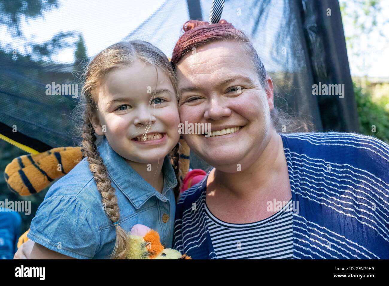 Lynwood, Washington, USA. Das vierjährige Mädchen und ihre Mutter umarmen sich und sind anhänglich. (MR) Stockfoto