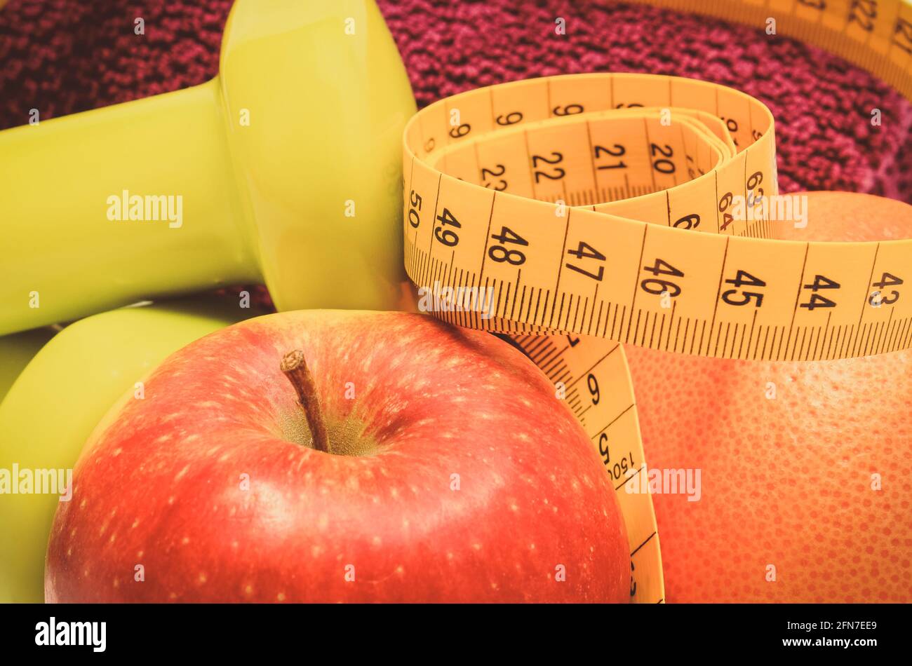 Maßband, frische reife Früchte und Kurzhanteln mit in Fitness. Abnehmen, gesunde Ernährung und sportliche Lebensstile Stockfoto