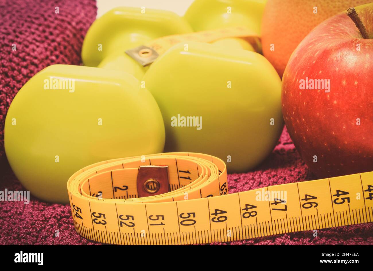 Maßband, frische reife Früchte und Kurzhanteln mit in Fitness. Abnehmen, gesunde Ernährung und sportliche Lebensstile Stockfoto