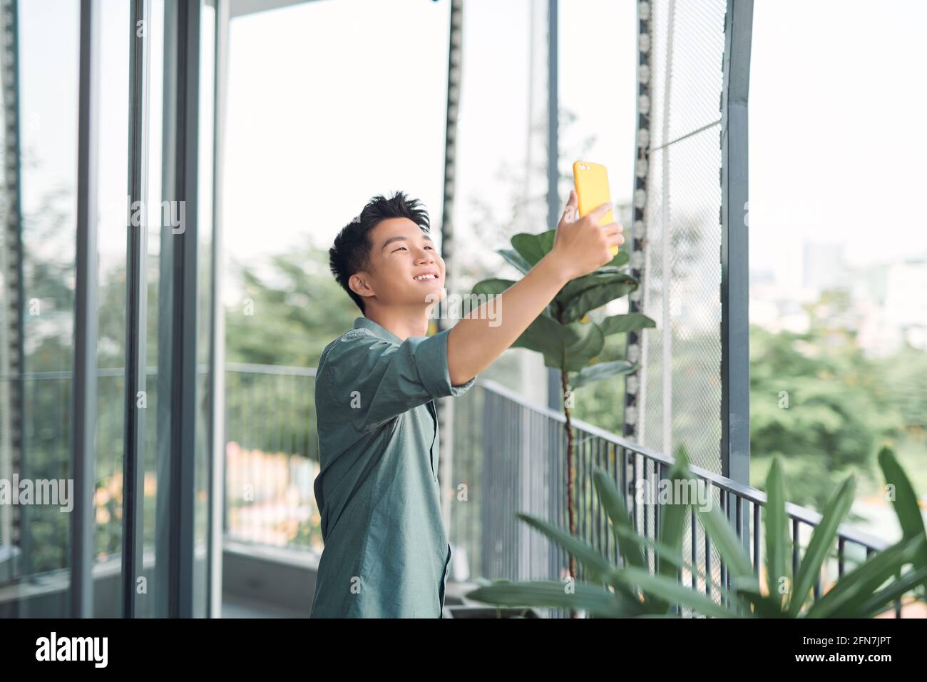 Junger asiatischer Mann, der ein Selfie auf dem Balkon nimmt Stockfoto