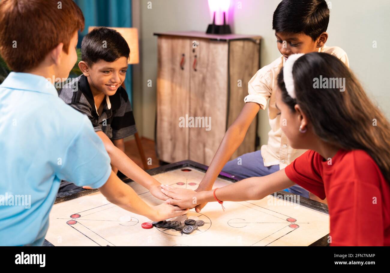 Konzentrieren Sie sich auf Carrom Coins, Gruppe von Kindern zu entscheiden, ob Paar Carrom spielen, indem sie klatschen oder die Hände auf Carrom-Brett zu Hause - Konzept der Kindheit Stockfoto