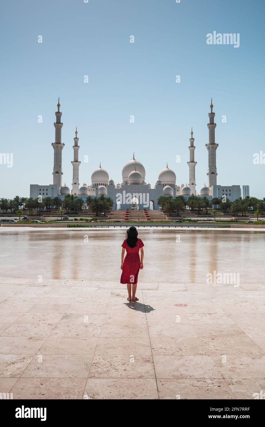 Frau genießt Aussicht Panoramablick auf die große Moschee Sheikh Zayed spiegelt sich im Wasser in Abu Dhabi, Vereinigte Arabische Emirate an einem sonnigen Tag. Große Moschee Stockfoto
