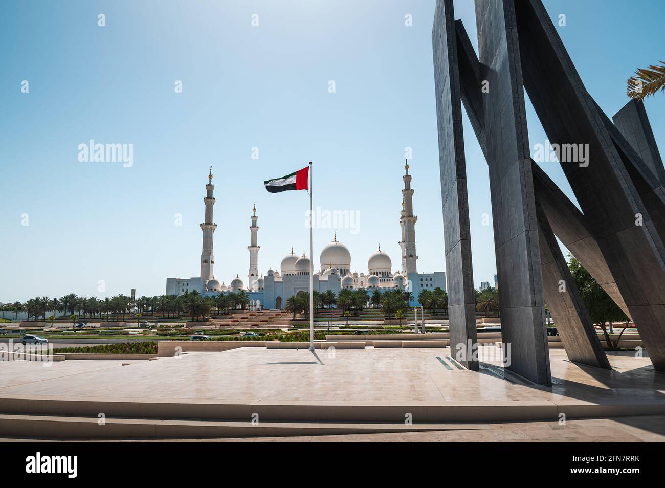 Scheich-Zayed-Moschee und Flagge der Vereinigten Arabischen Emirate in Abu Dhabi, Vereinigte Arabische Emirate an einem sonnigen Tag vom Wahat al Karama Memorial Park in der Hauptstadt der Vereinigten Arabischen Emirate gesehen Stockfoto