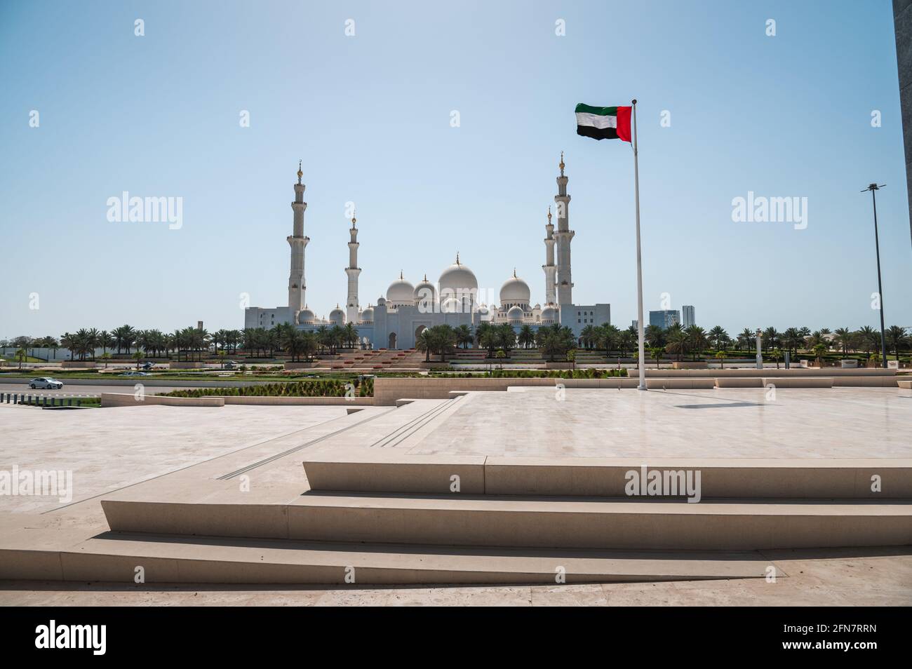 Scheich-Zayed-Moschee und Flagge der Vereinigten Arabischen Emirate in Abu Dhabi, Vereinigte Arabische Emirate an einem sonnigen Tag vom Wahat al Karama Memorial Park in der Hauptstadt der Vereinigten Arabischen Emirate gesehen Stockfoto