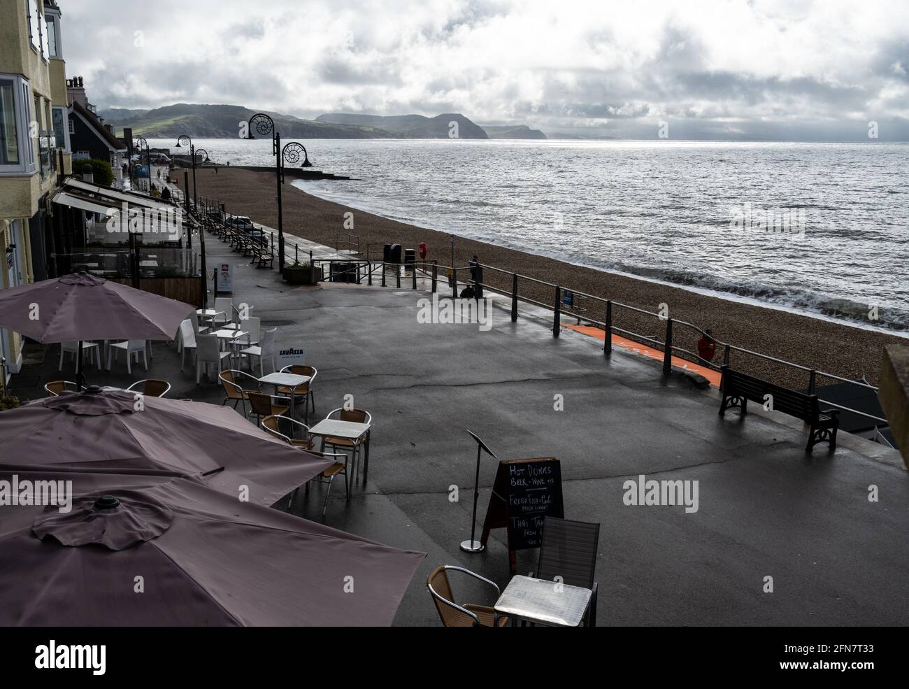 Lyme Regis, Dorset, Großbritannien. Mai 2021. Wetter in Großbritannien: Leere Cafeterien, brüllender Himmel und dunkle Wolken bringen unbeständiges Wetter an die Jurassic Coast. Für das Wochenende und für die nächste Woche werden ungeklärte Bedingungen prognostiziert. Kredit: Celia McMahon/Alamy Live Nachrichten. Stockfoto