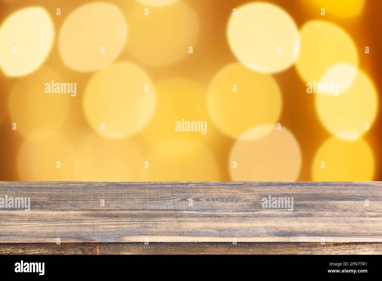 Holz Tischplatte auf verwischen gelben weihnachtsbaum Lichter Hintergrund Stockfoto