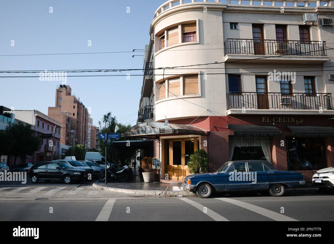 Cordoba, Argentinien - Januar 2020: Altmodisches blaues Auto, das an der Kreuzung in der Nähe des Cafés El Celta geparkt ist. Eingang zum Restaurant an der Ecke des Gebäudes Stockfoto