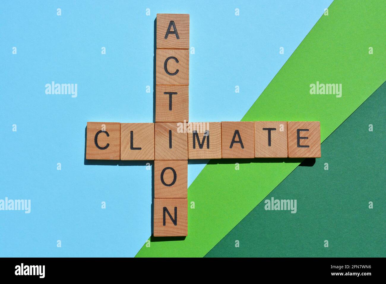 Climate Action, Wörter in Holzbuchstaben in Kreuzworträtsel-Form isoliert auf blaugrünem Hintergrund Stockfoto