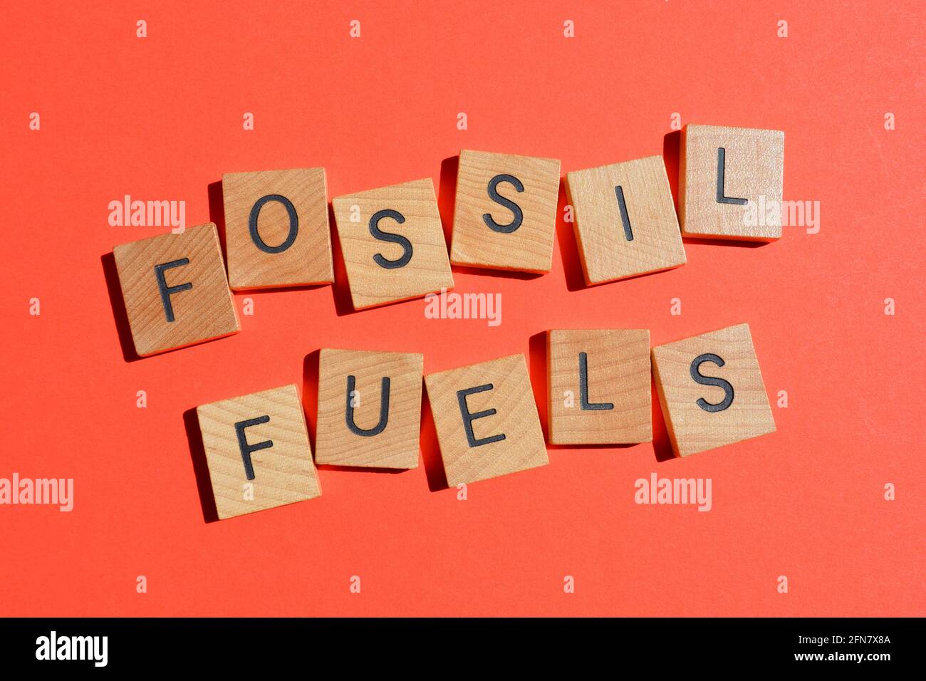Fossile Brennstoffe, Wort in Holzbuchstaben isoliert auf rotem Hintergrund Stockfoto