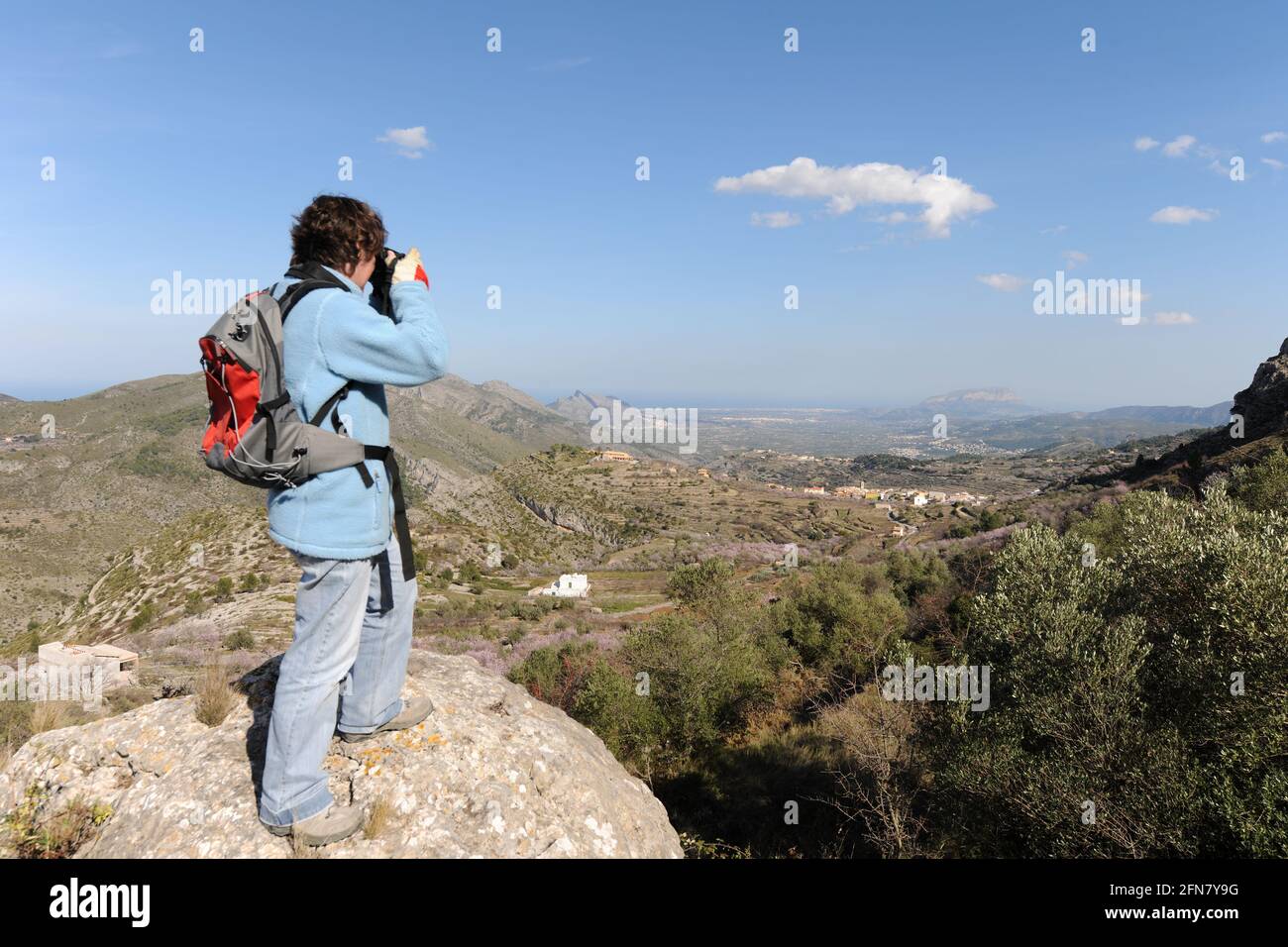 Wanderer mit Rucksack, der ein Foto von der Aussicht von Benimaurell auf die Mittelmeerküste, Provinz Alicante, Spanien macht Stockfoto