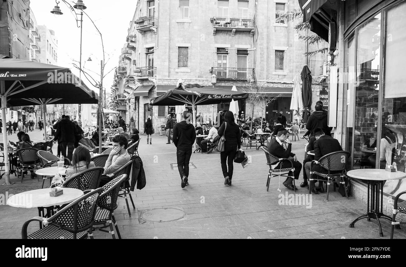 Leute, die abends auf der Cafeterrasse in der Jaffa Road Street sitzen. Die Jaffa Road ist eine der längsten und ältesten Hauptstraßen Jerusalems. Schwarz-weiß Stockfoto