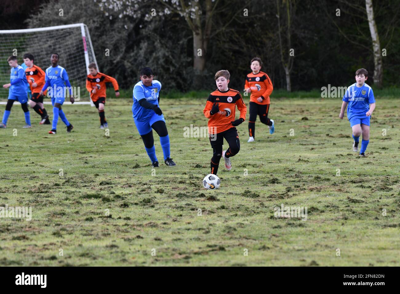 Juniorfußballspiel-Action für Jungen auf unebenem Spielfeld Großbritannien Stockfoto