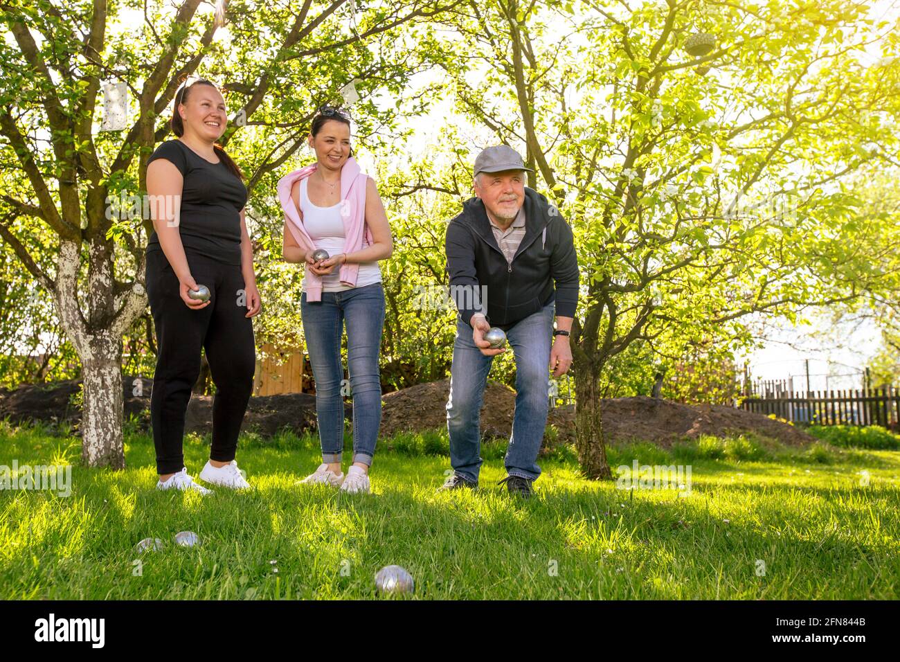 Eine fröhliche, positiv lächelnde Familie, die an einem schönen Sommertag im Garten im traditionellen französischen Petanque-Spiel spielt und die Freizeit genießt Stockfoto
