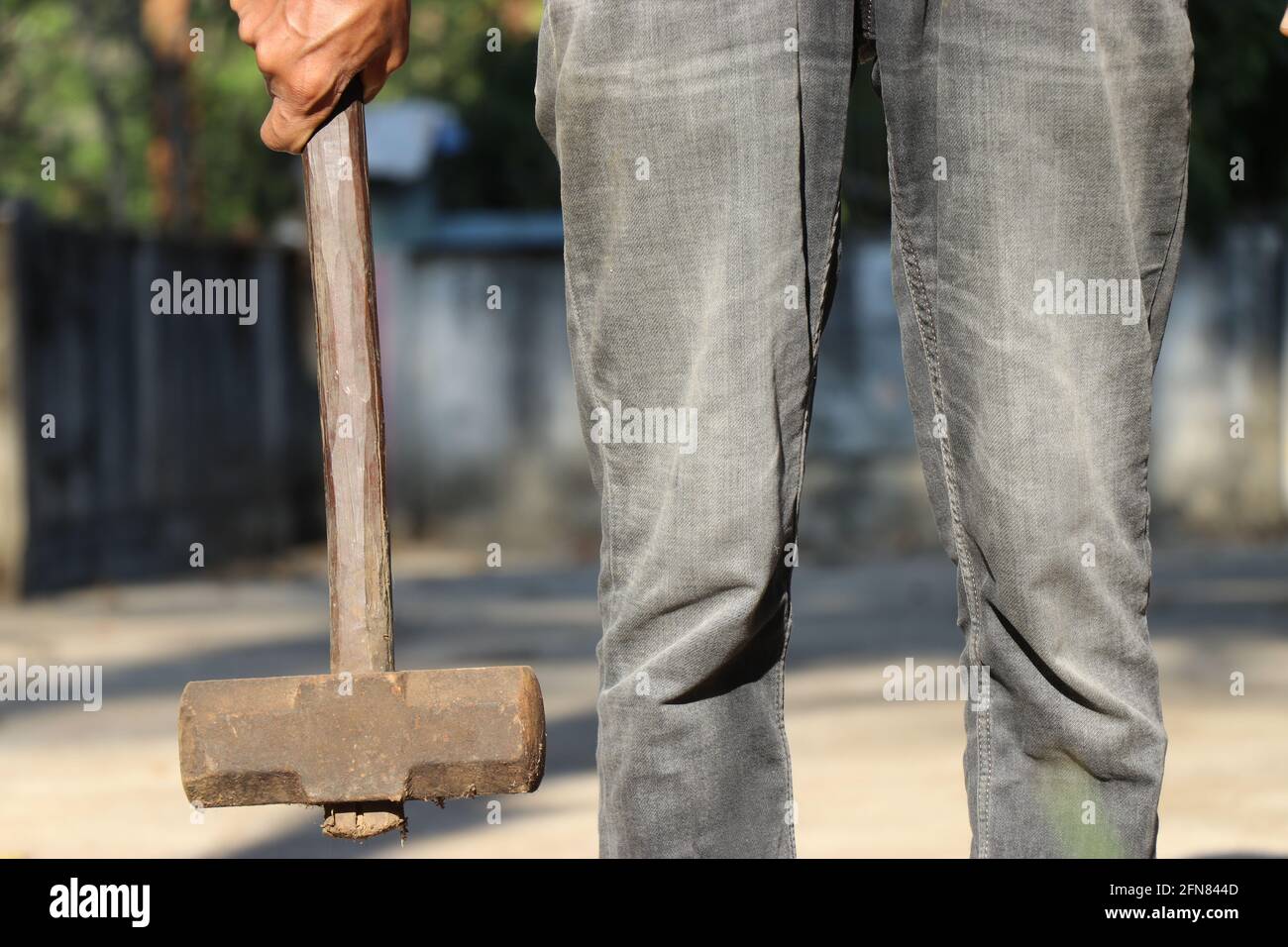 Mann, der einen alten und rostigen Hammer mit Holzgriff an einer Hand hält. Hammer, das Eisenwerkzeug für Konstruktionszwecke ist Stockfoto