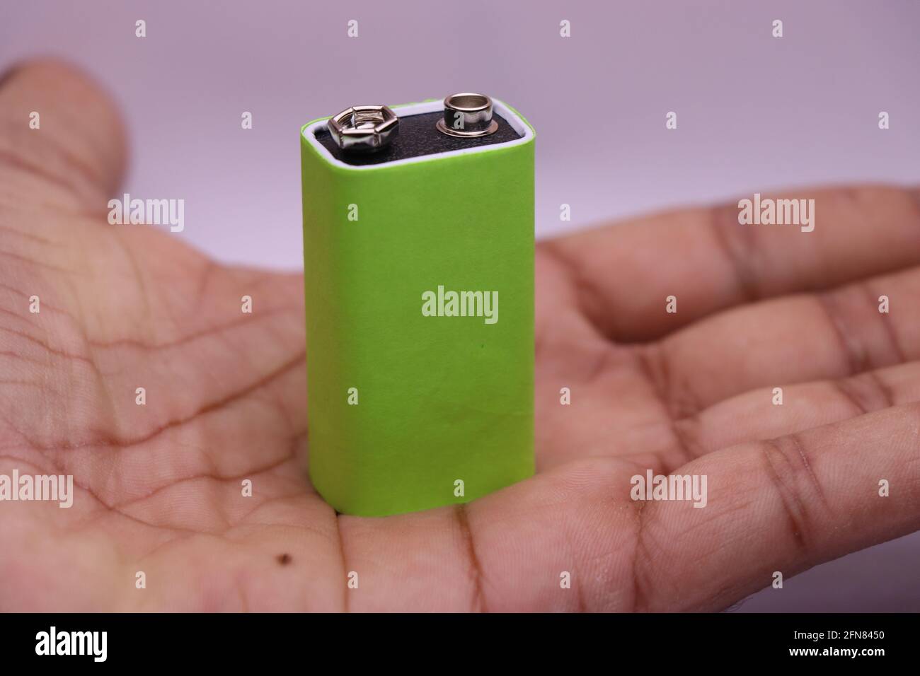 9-v-Batterie mit grünem Bildschirm zum Drucken von Markenetiketten in der Hand. Alkalibatterie in der Hand gehalten Stockfoto