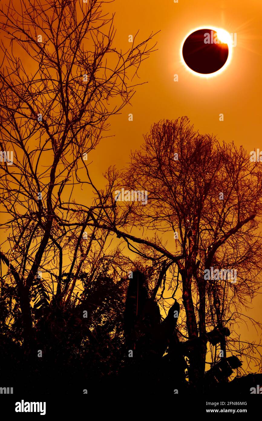 Erstaunliches wissenschaftliches Naturphänomen. Prominenz und innere Sonnenkorona. Totale Sonnenfinsternis mit Diamantring-Effekt, der oben am orangefarbenen Himmel leuchtet Stockfoto