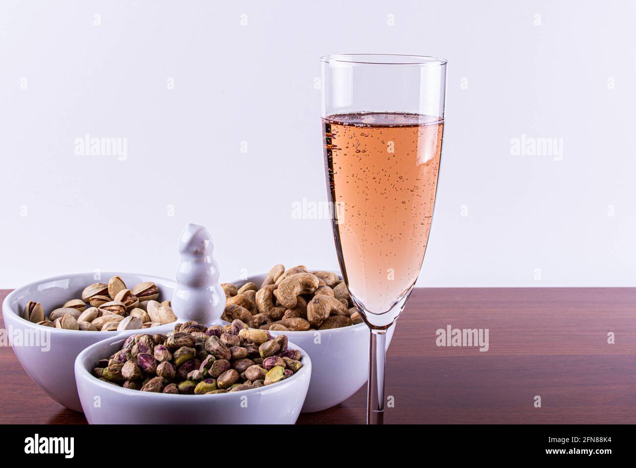Glas Sekt in Pink mit gemischten Nüssen. . Stockfoto