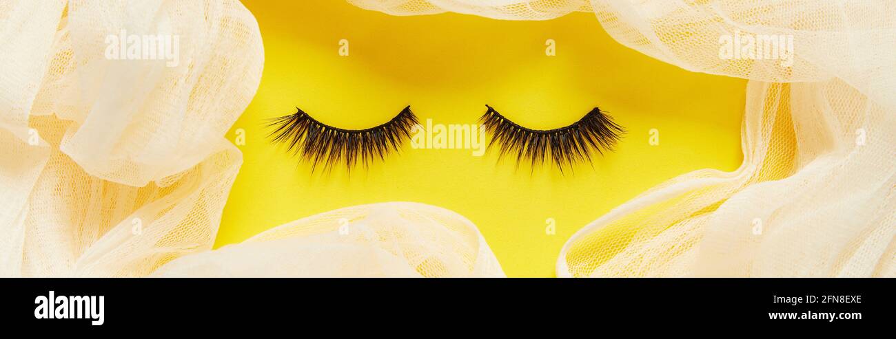 Kreatives Layout mit Wimpern. Geschlossene Augen auf gelbem Hintergrund Stockfoto