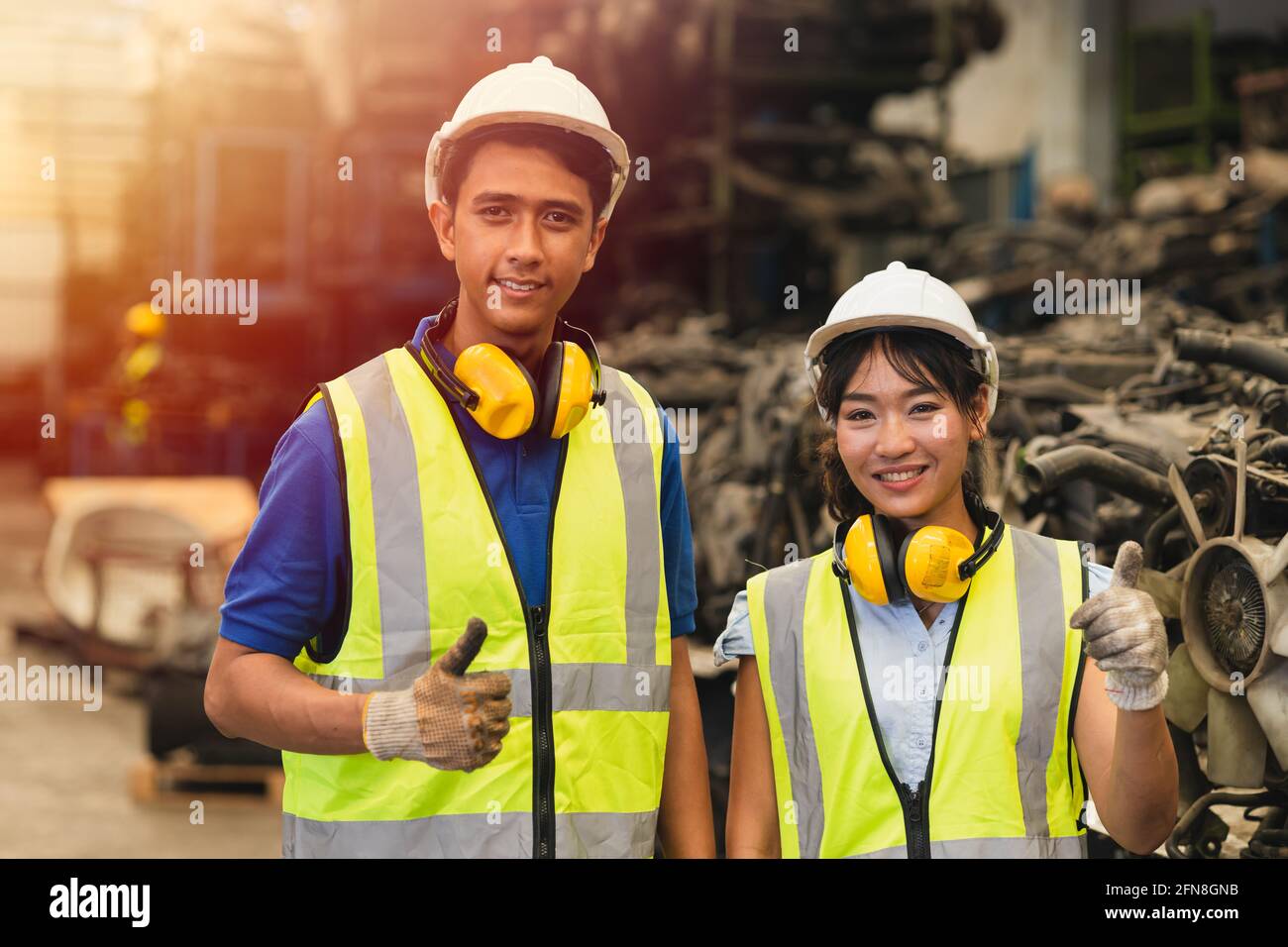 Portrait zwei asiatische junge Männer und Frauen, die arbeiten, Daumen hoch Ein paar Freund Teamingenieur, der zusammen arbeitet, lächelt glücklich Arbeiten in der Fabrikindustrie Stockfoto