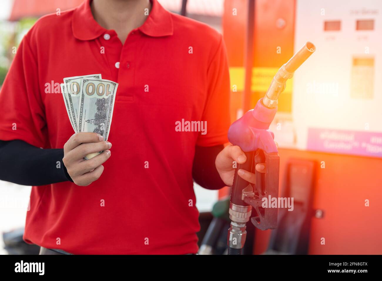 Konzept zur Kraftstoffkosteneinsparung, Mitarbeiter halten Geld zurück an der Tankstelle Stockfoto