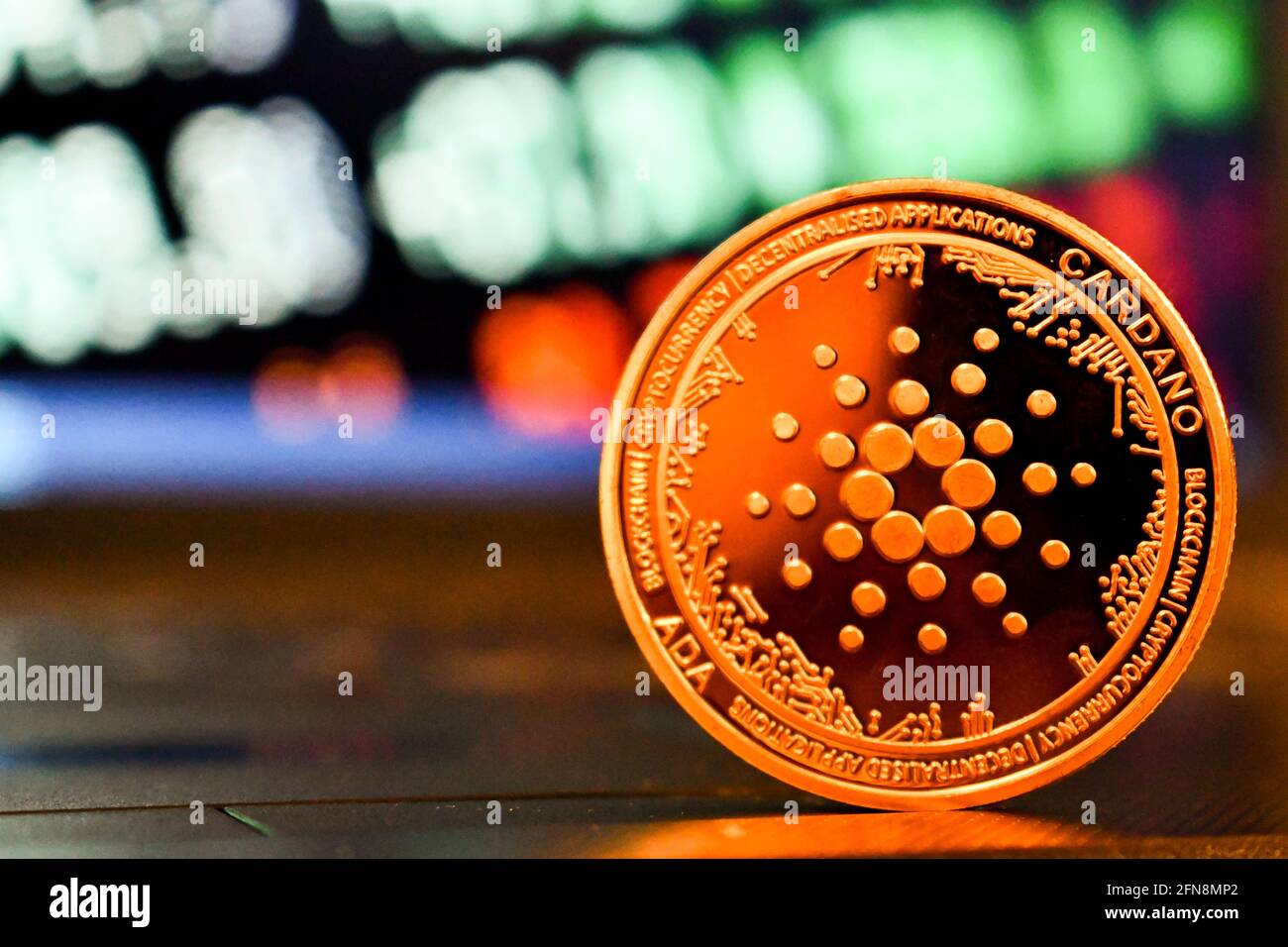 Cardano Kryptowährung Token ist vor einem Computer zu sehen Bildschirm mit verschwommenen Aktienkursen Stockfoto