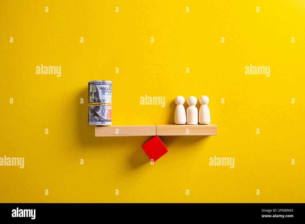 Holzleute und ein Dollarbündel auf der Waage. Einsparung des Budgets des Unternehmens. Durchschnittseinkommen, Löhne Stockfoto