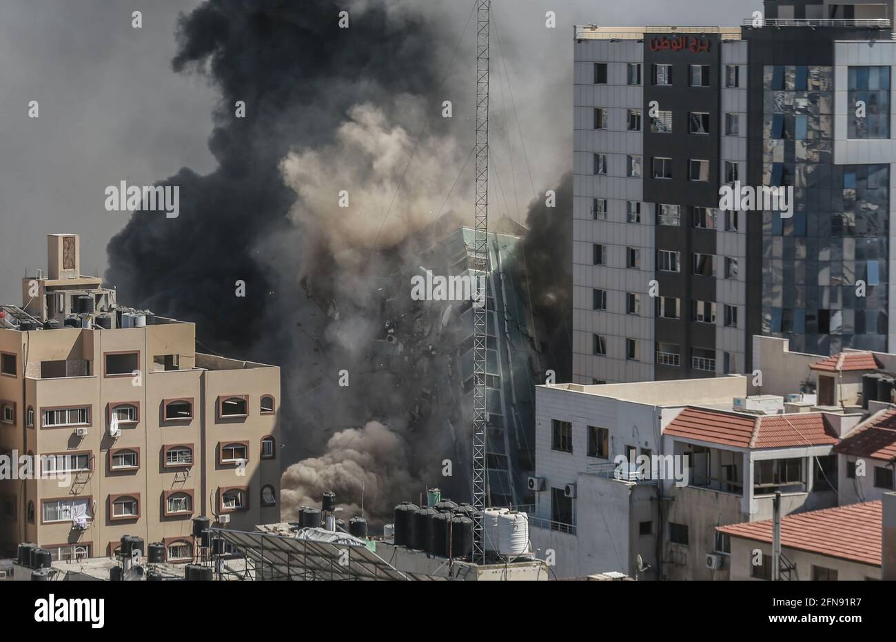 Gaza-Stadt, Palästinensische Gebiete. Mai 2021. Der Al-Jalaa-Turm, in dem Wohnungen und mehrere Medien, darunter die Associated Press und Al Jazeera, untergebracht sind, bricht zusammen, nachdem er von israelischen Luftangriffen getroffen wurde, inmitten des eskalierenden Ausbruchs der israelisch-palästinensischen Gewalt. Kredit: Mohammed Talatene/dpa/Alamy Live Nachrichten Stockfoto