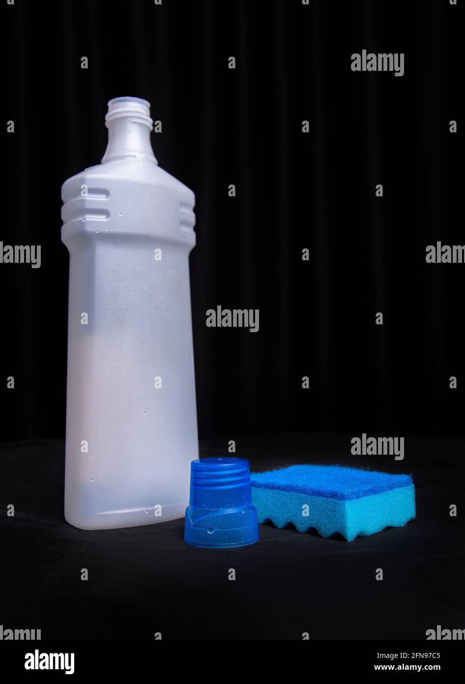 Blauer Schwamm mit einer Flasche Reinigungsmittel auf schwarzem Hintergrund. Stockfoto