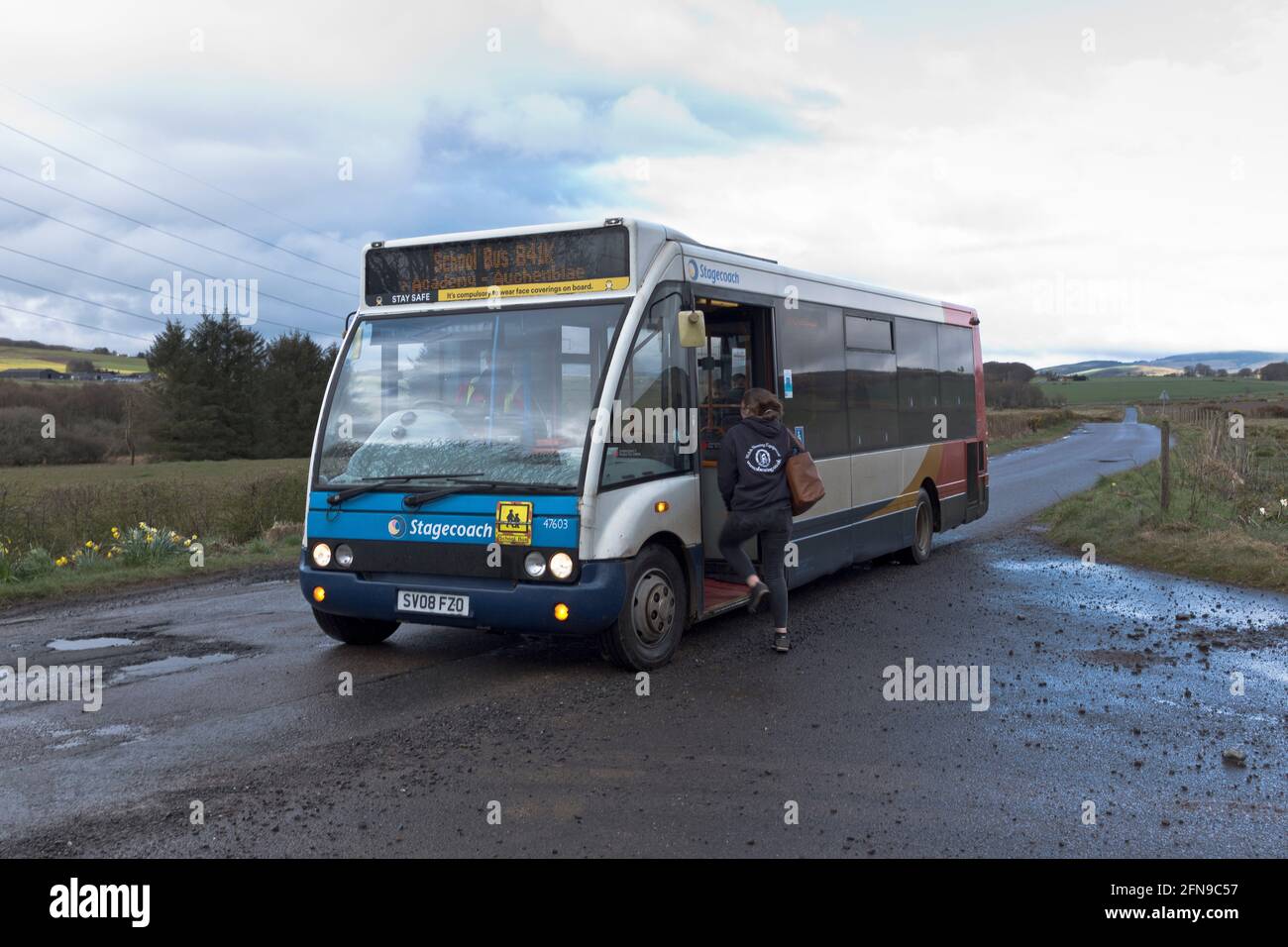 dh Schulbus SCHOTTLAND Großbritannien ländlicher Schulbus Abholung Teenager Kind auf der Landstraße Kinder halten auf dem Land Stockfoto