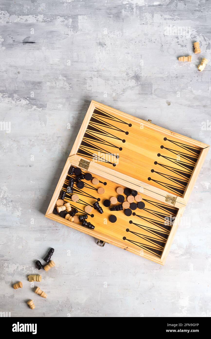 Backgammon Würfel und Stücke mit einem Paar Schachfiguren auf dem Steinhintergrund, flach liegend Stockfoto