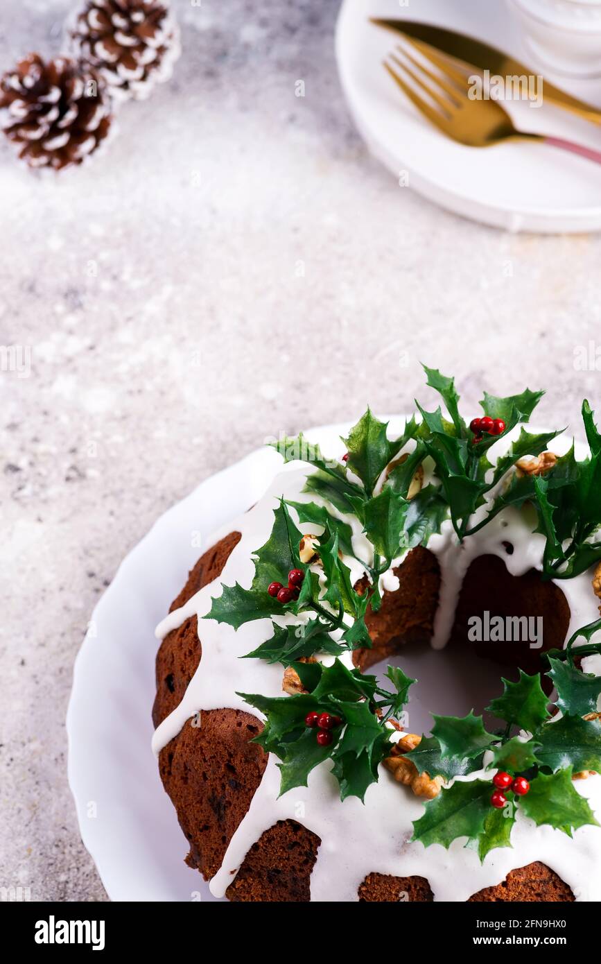 Weihnachten hausgemachten dunklen Schokolade gebündelt Kuchen mit Holly Beere verziert Äste auf Stein Stockfoto