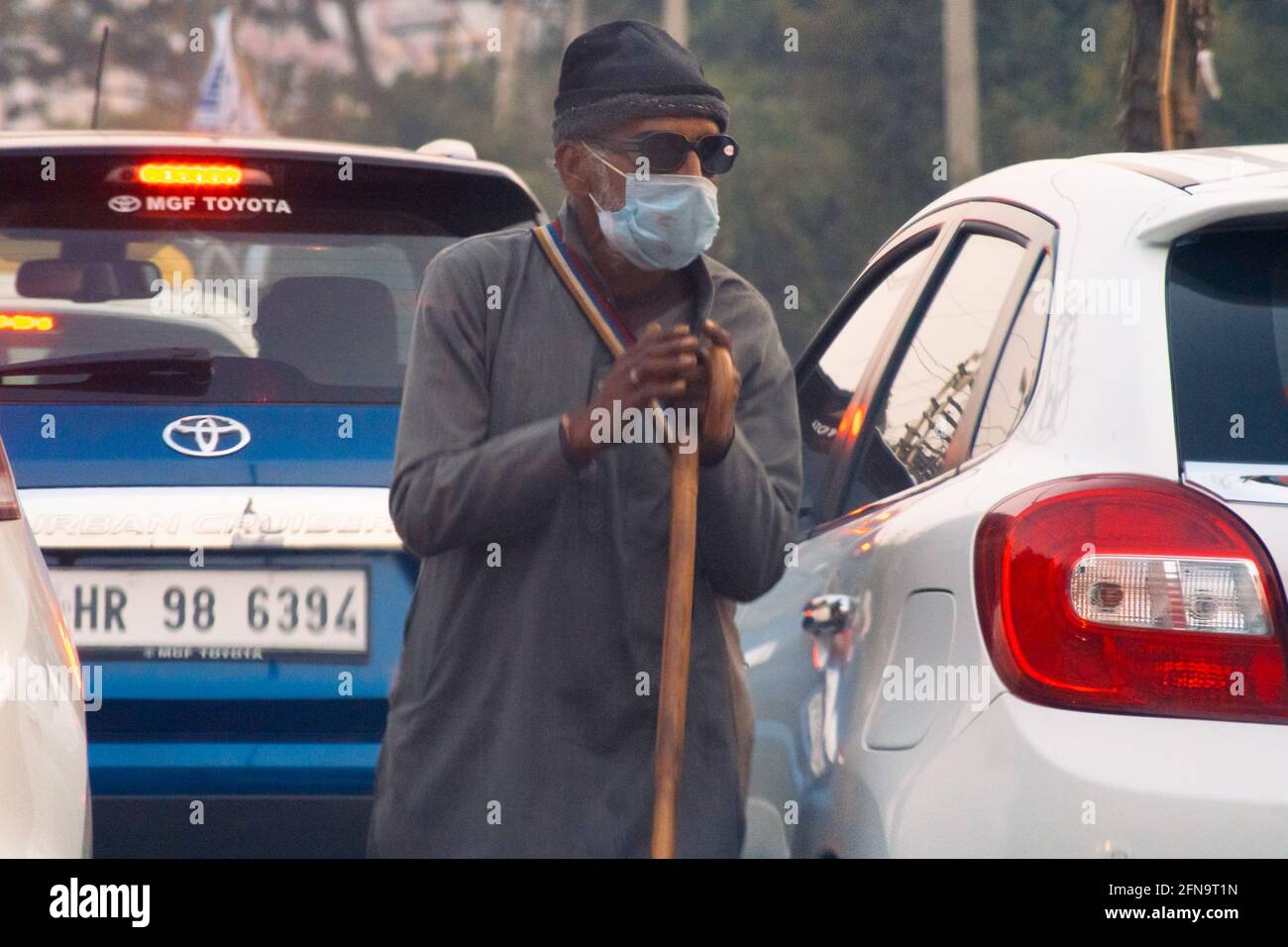 Alte Armut heimgesucht verzweifelter hungriger Mann bettelt auf der Straße Das Tragen einer Maske während der tödlichen Coronavirus covid 19 Pandemie Wie die Menschen in ihren bleiben Stockfoto