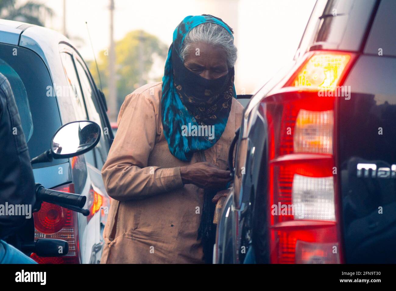 Alte, von Armut geplagte, verzweifelte, hungrige Dame, die auf der Straße bettelte Das Tragen einer Maske während der tödlichen Coronavirus covid 19 Pandemie Wenn die Leute bleiben Stockfoto