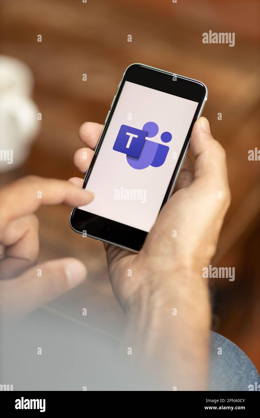 Mann, der ein Smartphone in einem Café hält. Microsoft Teams-Logo auf dem Display. Selektiver Fokus. Stockfoto