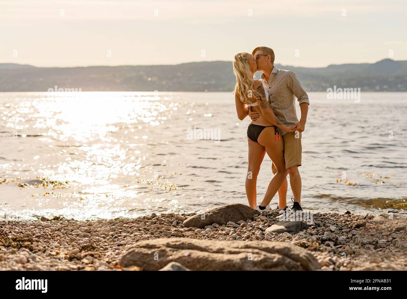 Junges und schönes liebevolles Paar küssen am Strand Stockfoto