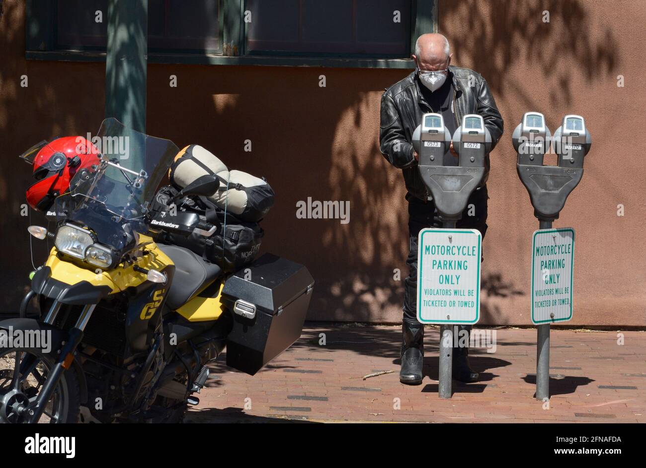 Ein Tourist, der Santa Fe, New Mexico, besucht, parkt sein BMW F650 GS Motorrad und legt Münzen in einen Parkuhr in Santa Fe, New Mexico, ein. Stockfoto