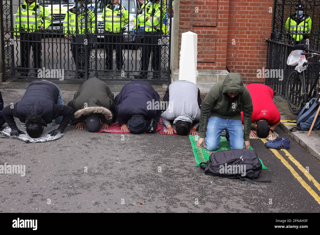 London, Großbritannien. Mai 2021. Muslimische Demonstranten, die an einer Anti-Israel-Demonstration in London teilnehmen, nehmen sich einen Moment Zeit, um vor Toren in der Nähe des Kensington Palace zu beten. Quelle: Joe Kuis /Alamy News Stockfoto